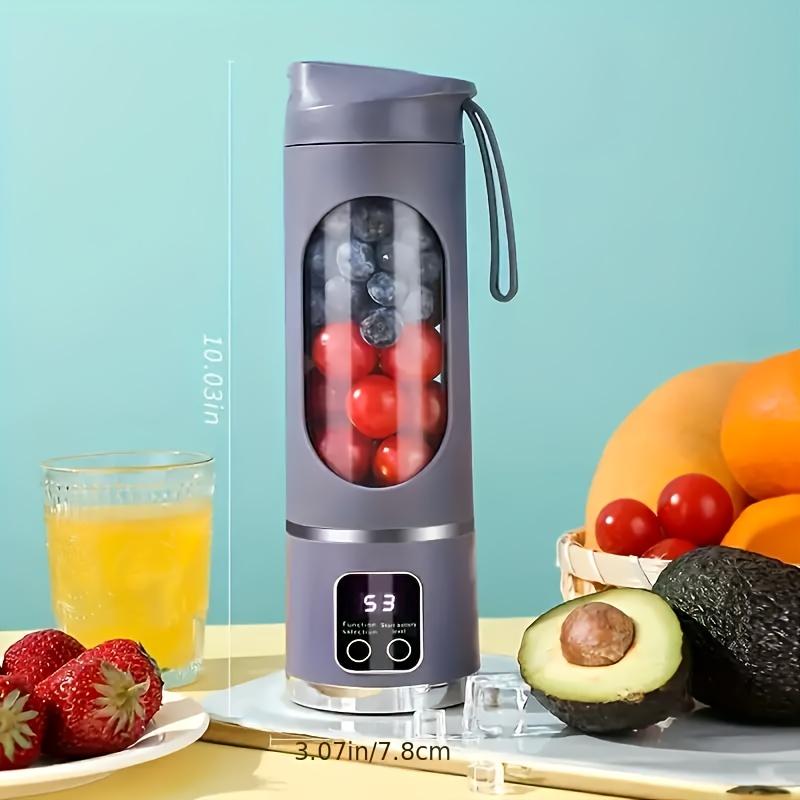 Portable blender with fruits and a glass of juice on a light blue background